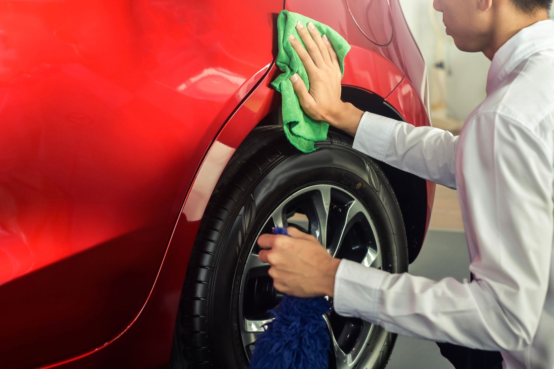 Applying paint protection on a red sports car.